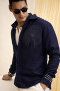 Man wearing a navy blue hoodie with a spiral design, sunglasses, and white pants.